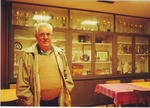 Un hombre posa junto a vitrinas con trofeos